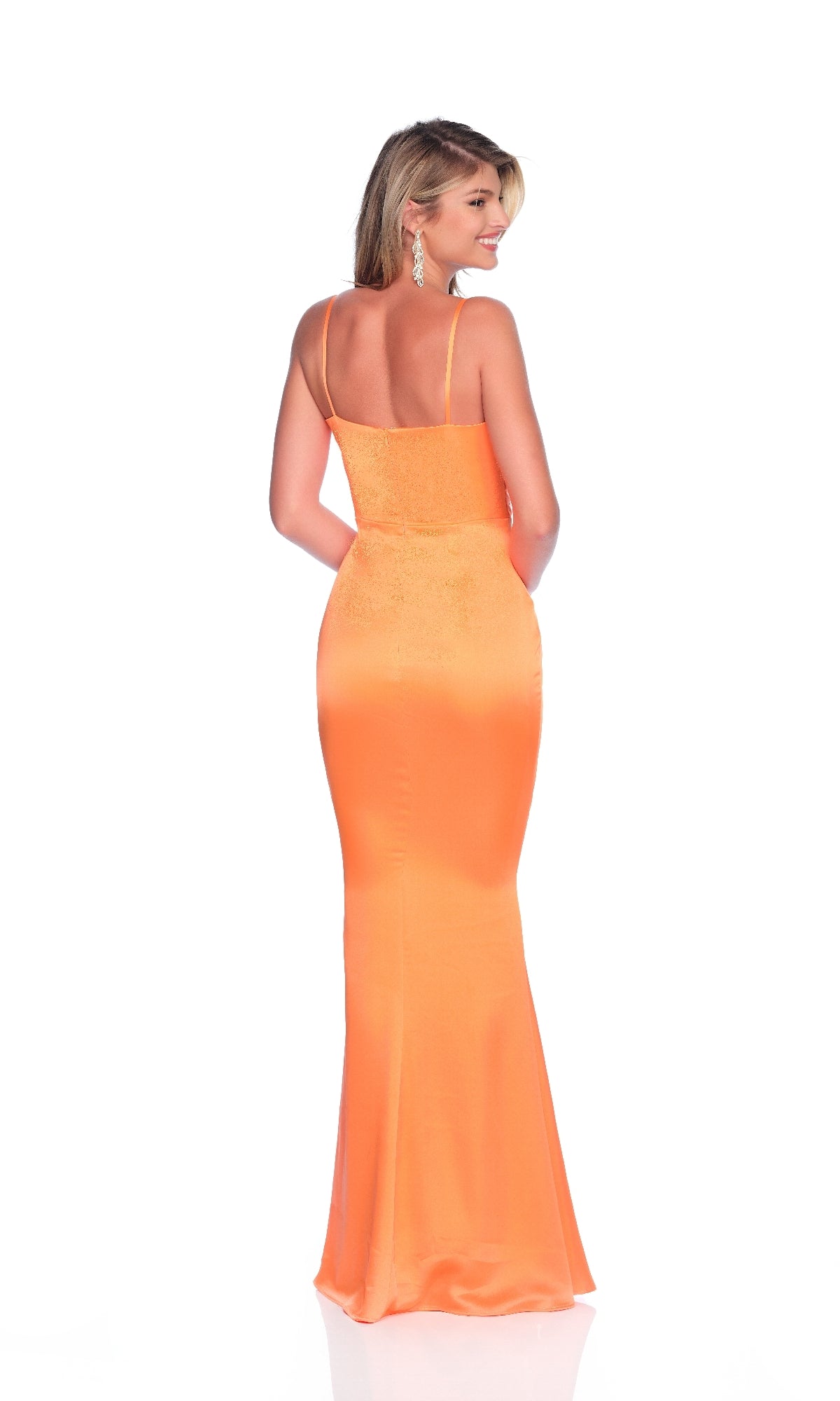 Woman in the Dave and Johnny 12101 long prom dress—an orange, fitted, floor-length gown with thin straps and an embellished neckline—stands smiling, facing away from the camera against a white background.